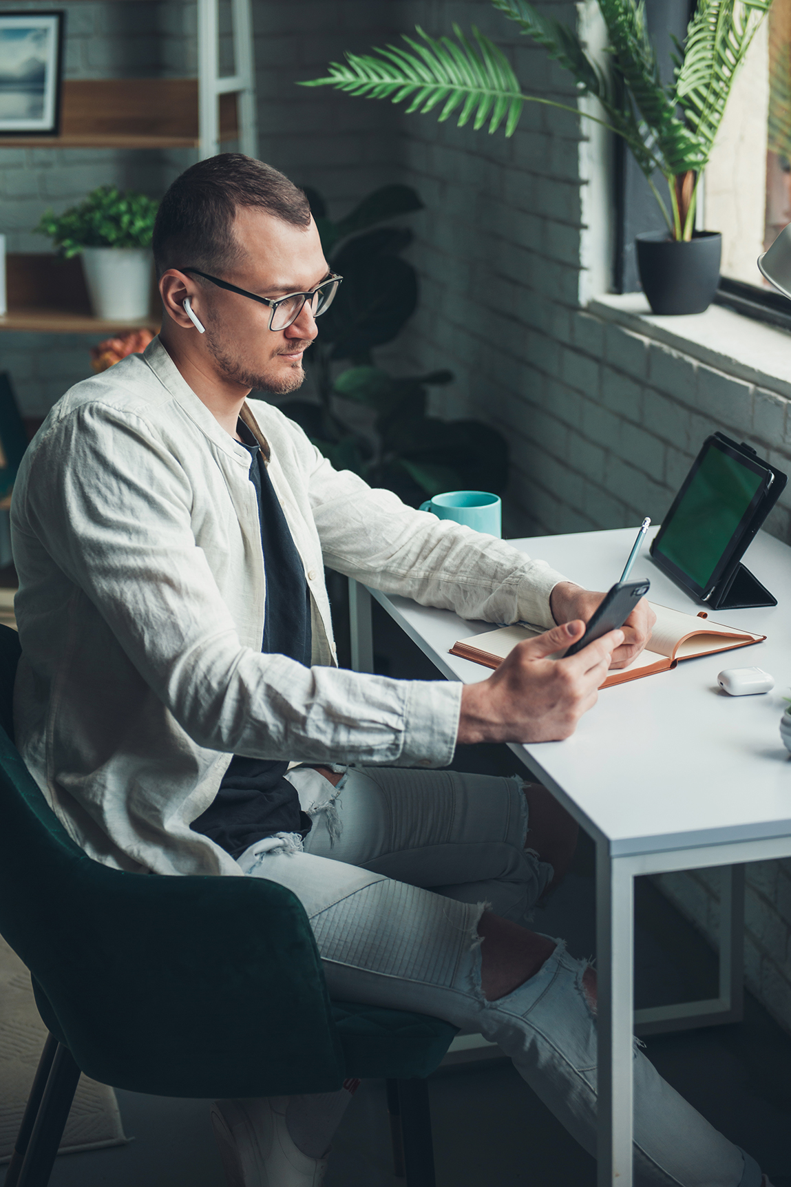Business man writing on paper notebook on office table during working from home, using tablet and mobile phone. Business portrait. Education concept. Distance education. desk posture photo