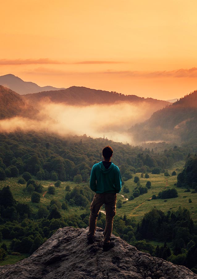 Traveler man standing on peak of cliff in mountains at sunset. peaceful photo