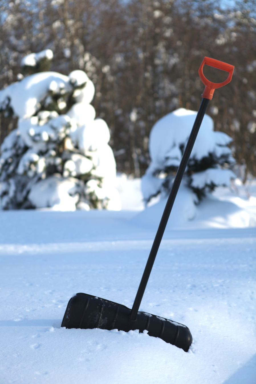 Black snow shovel with yellow handle stick in snow winter is a workout photo