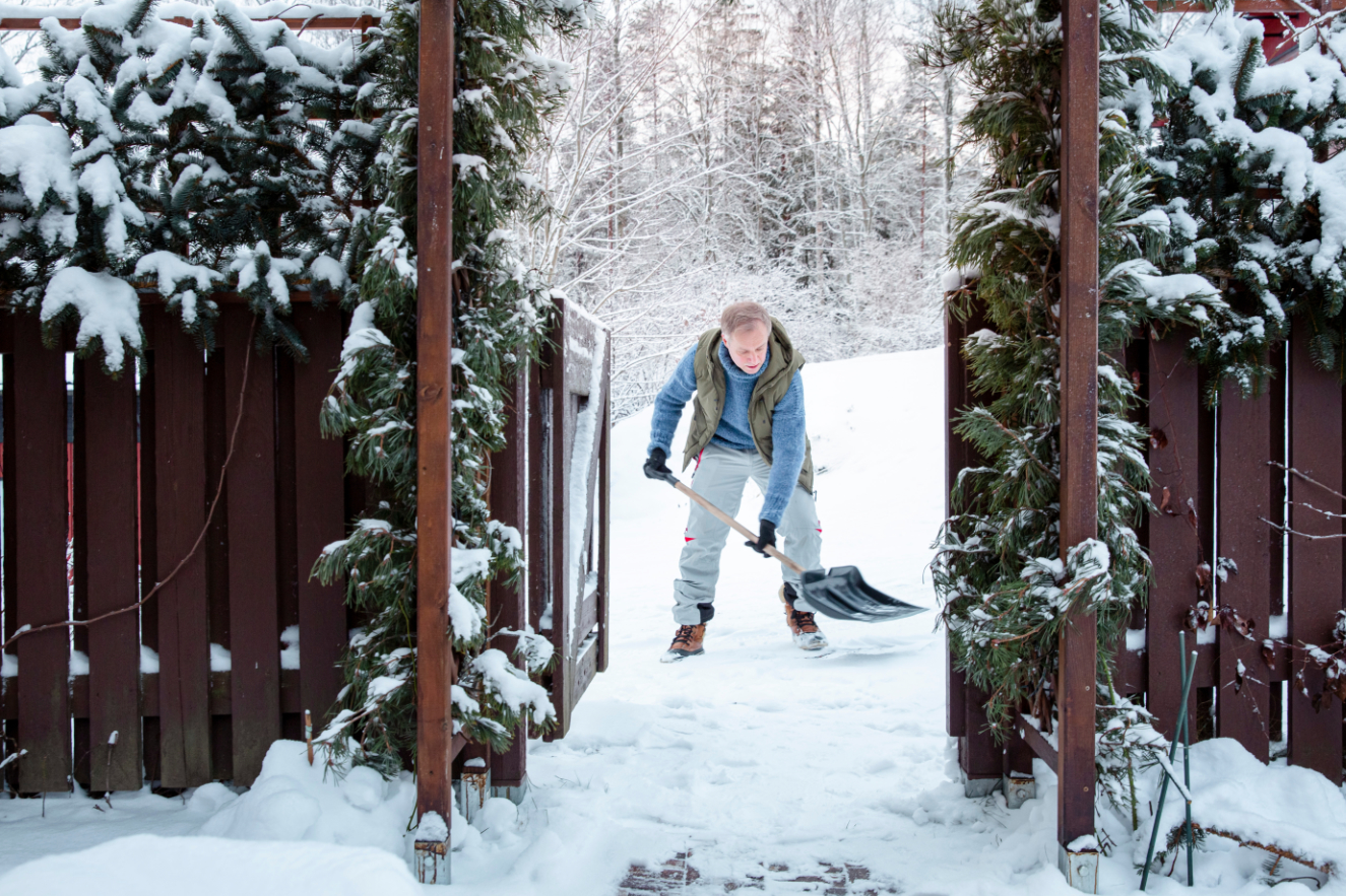 Man shoveling snow in backyard on a wintry morning, bundled in warm gear, highlighting everyday outdoor routine and seasonal lifestyle. Man shoveling snow