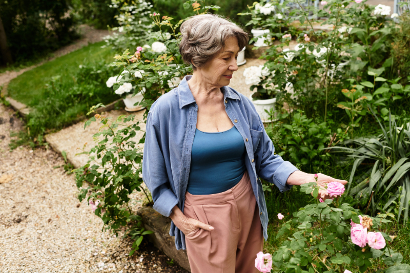 garden-movement photo of Senior woman admires the vibrant blossoms while tending to her lush garden during the day.